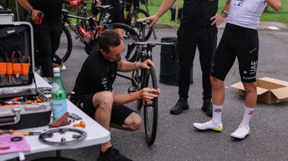 UAE Team EmirGeates&#039; Slovenian rider Tadej Pogacar (R) looks on as team mechanics adjust his bicycle before taking part in a team training session, on June 29, 2023