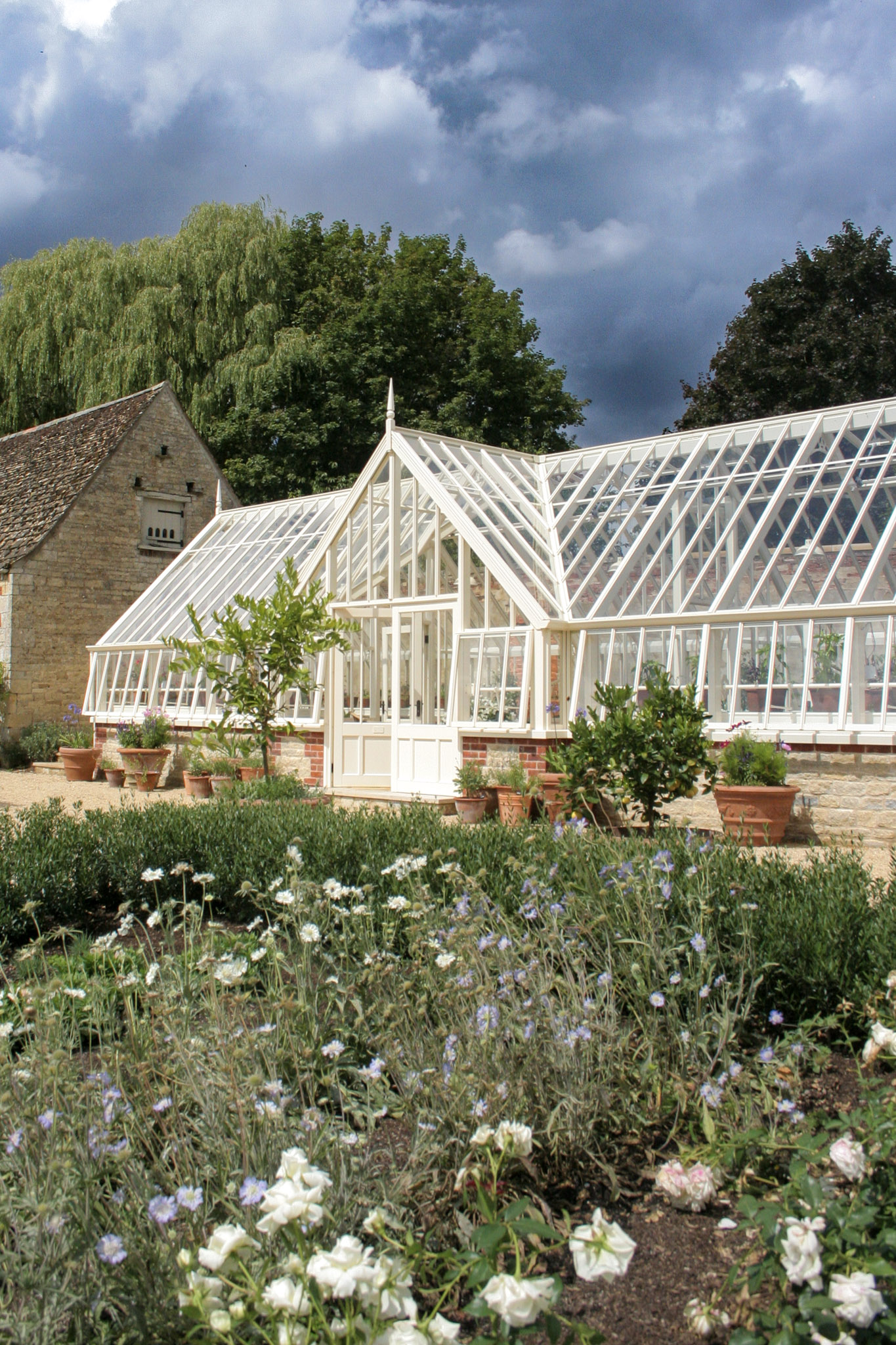 beautiful white greenhouse surrounded by flowers and greenery