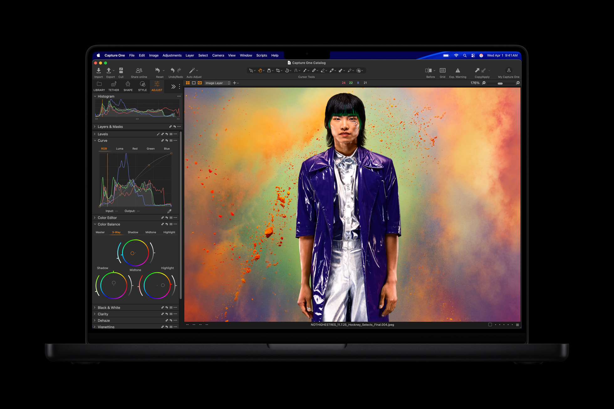 A MacBook Pro running Capture One shows a professional photo editing workspace featuring a portrait of a person in a purple coat against a colorful, textured background.