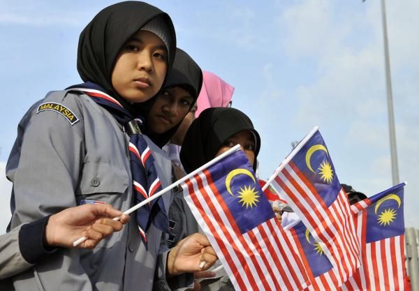 Local children wave the Malaysian flag at the roadside