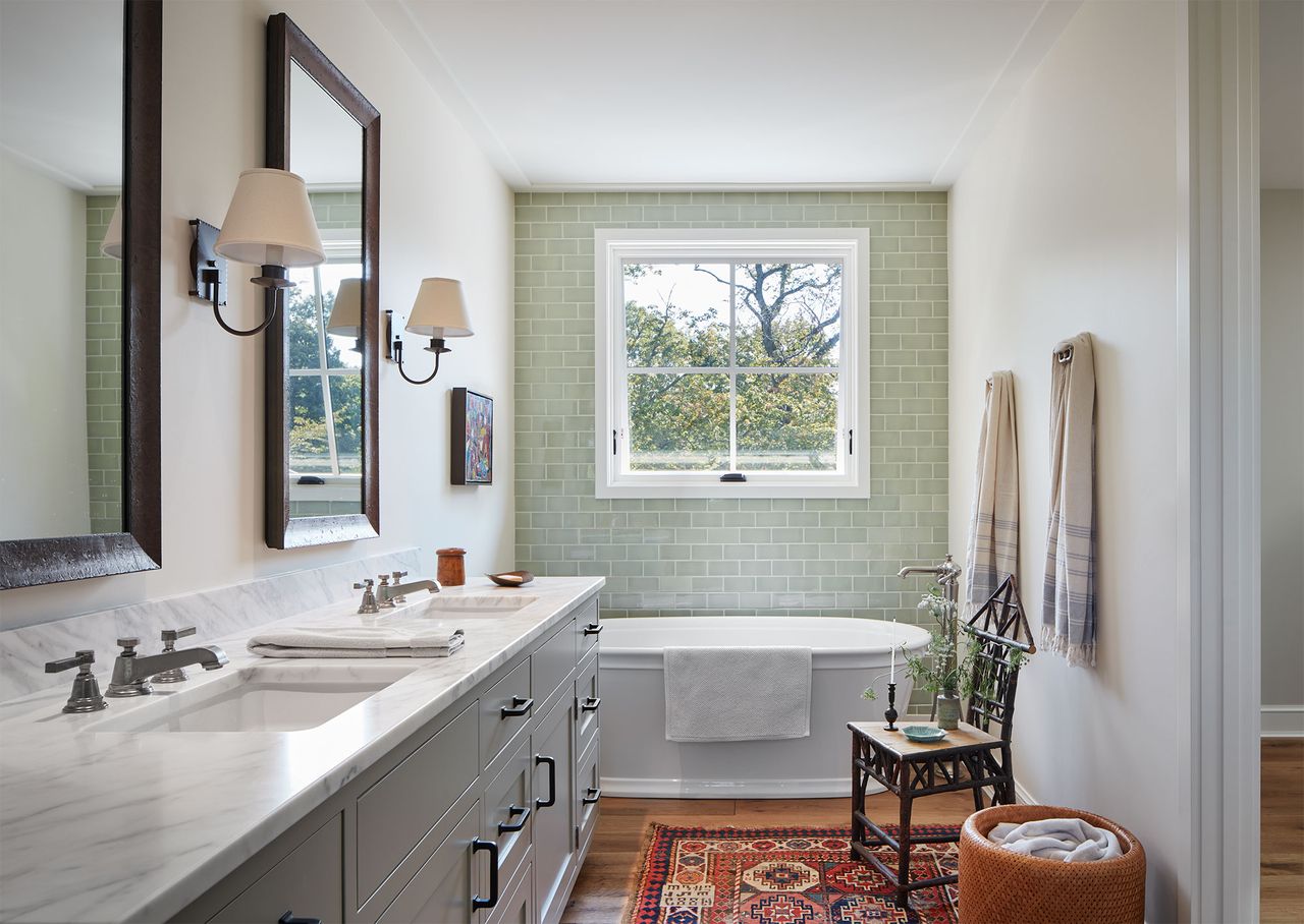 bathroom with pale green chandelier tiles freestanding double sink tub and traditional kilim rug and antique chair and wall lamps