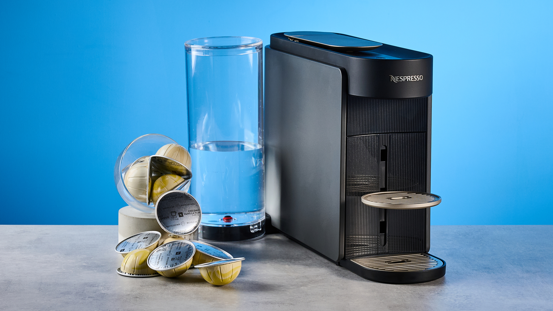 the nespresso vertuo up machine photographed against a blue background
