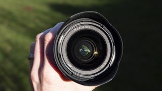 Close up of the Sony FE 24-50mm F2.8 G lens front element in the hand