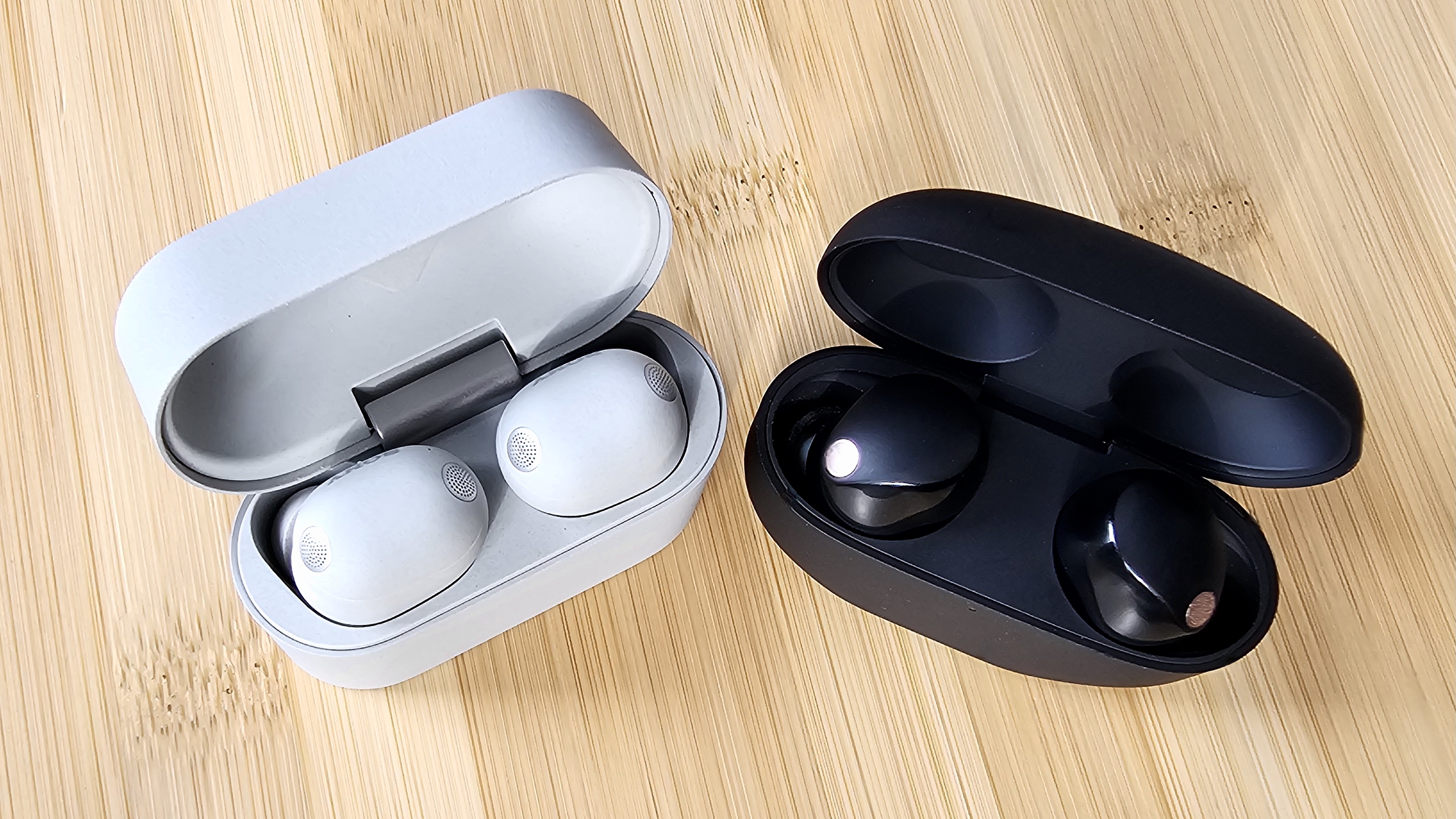 The Sony WF-1000XM6 and WF-1000XM5 side by side in a comparison, on a light wood table 