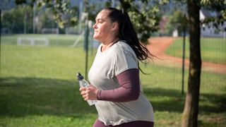 Woman holding water bottle while running