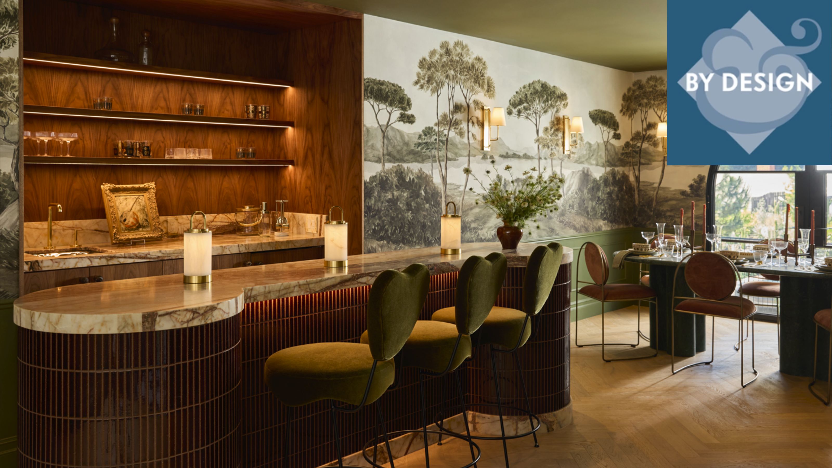 Luxurious home bar set-up with wooden shelving, marble countertop, cuved kitchen island with dark wood base, marble countertop, mural to the right-hand side in dining area with table and chairs