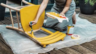 a person painting a chair with yellow paint