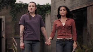 Bella Ramsey as Ellie and Isabela Merced as Dina hold hands on The Last of Us Season 2.