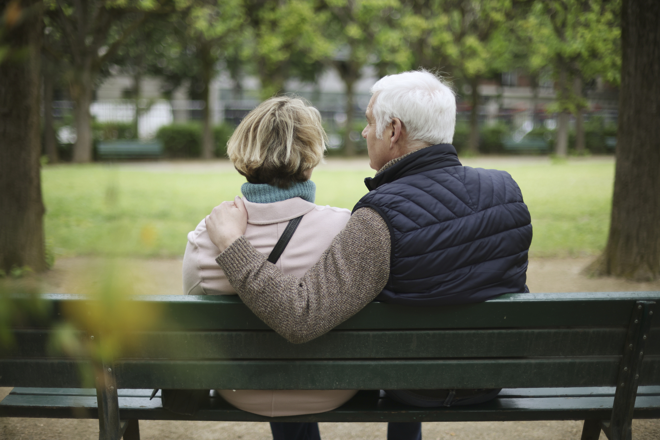Pensioner couple sitting on park bench