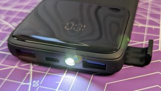 Close up of the Iniu B6 power bank showing the charge ports, the LED torch, the phone holder and the digital capacity display