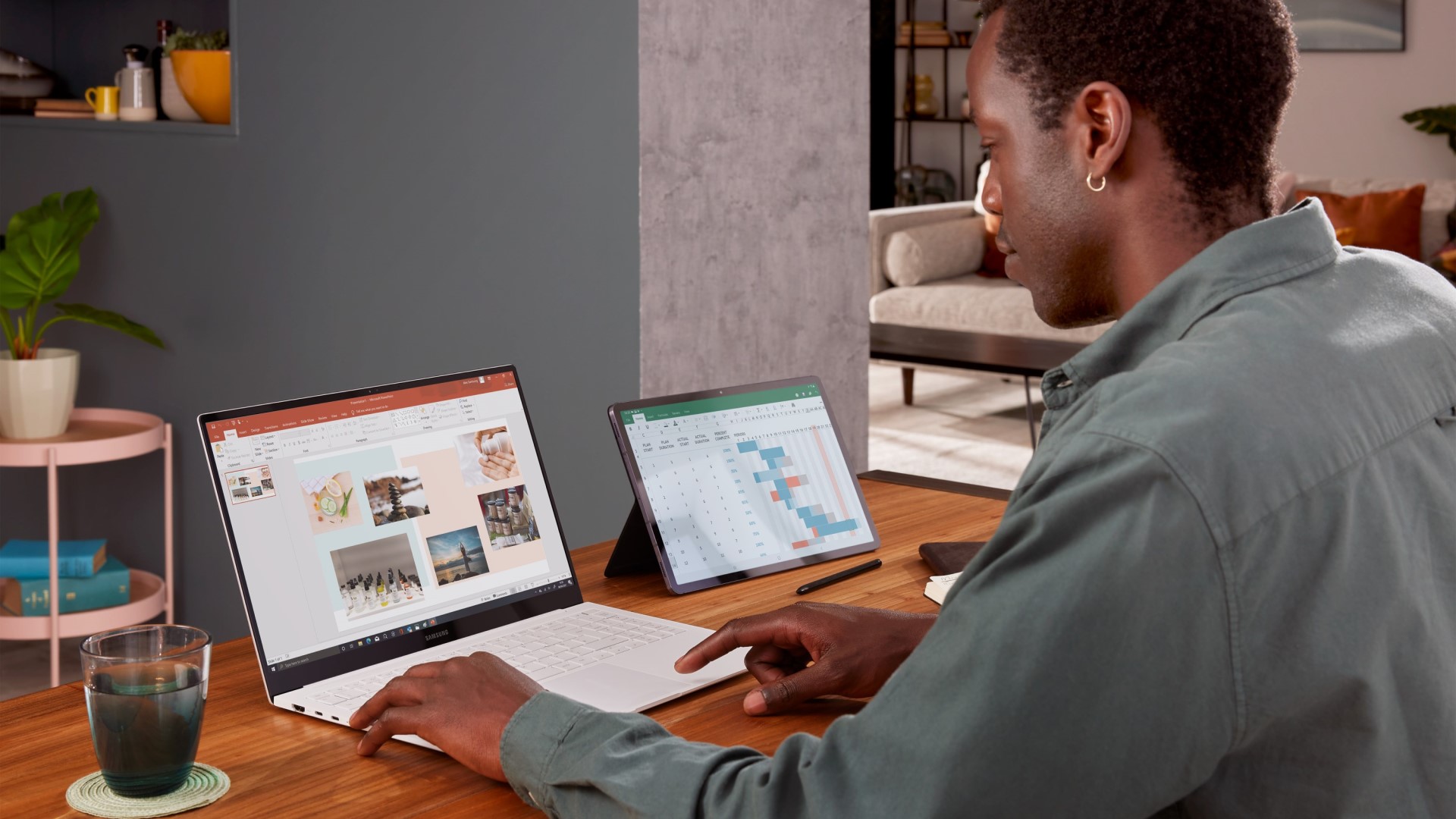 Man sitting at desk using a laptop and a tablet to work