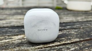 Sony LinkBuds Fit in-ear headphones charging case on wooden outdoor table