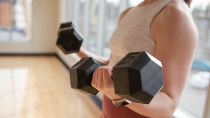 A woman performing dumbbell bicep curls as part of an arm workout 