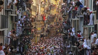 People standing on balconies look at participants as they run in front of Alcurrucen's bulls during the first bull run of the San Fermin Festival, on July 7, 2013, in Pamplona, northern Spain