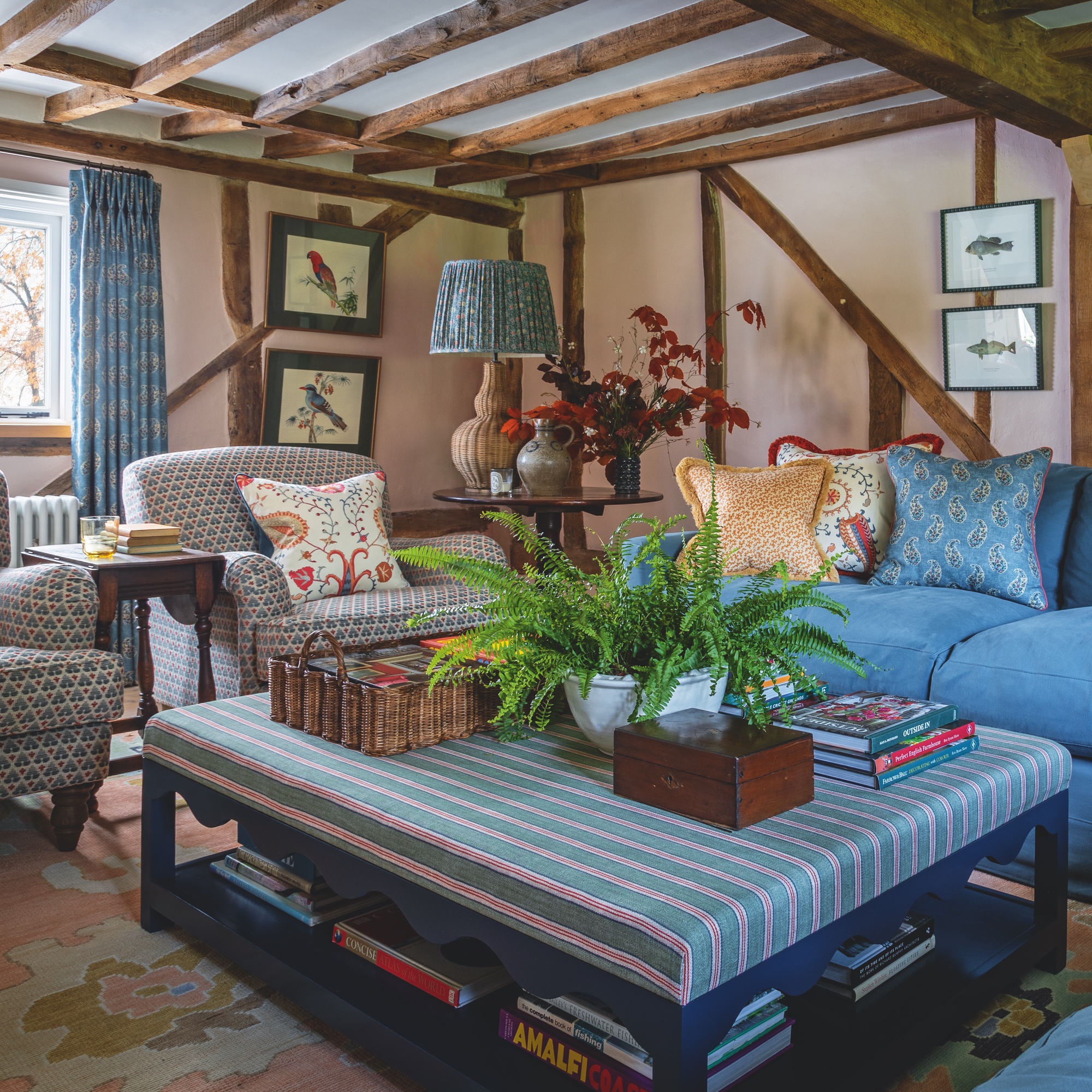 sitting room in English farmhouse with beamed ceiling, pink walls and upholstered furniture