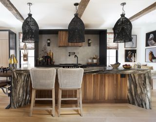 A kitchen with black fabric pendant lights, and a large marble island