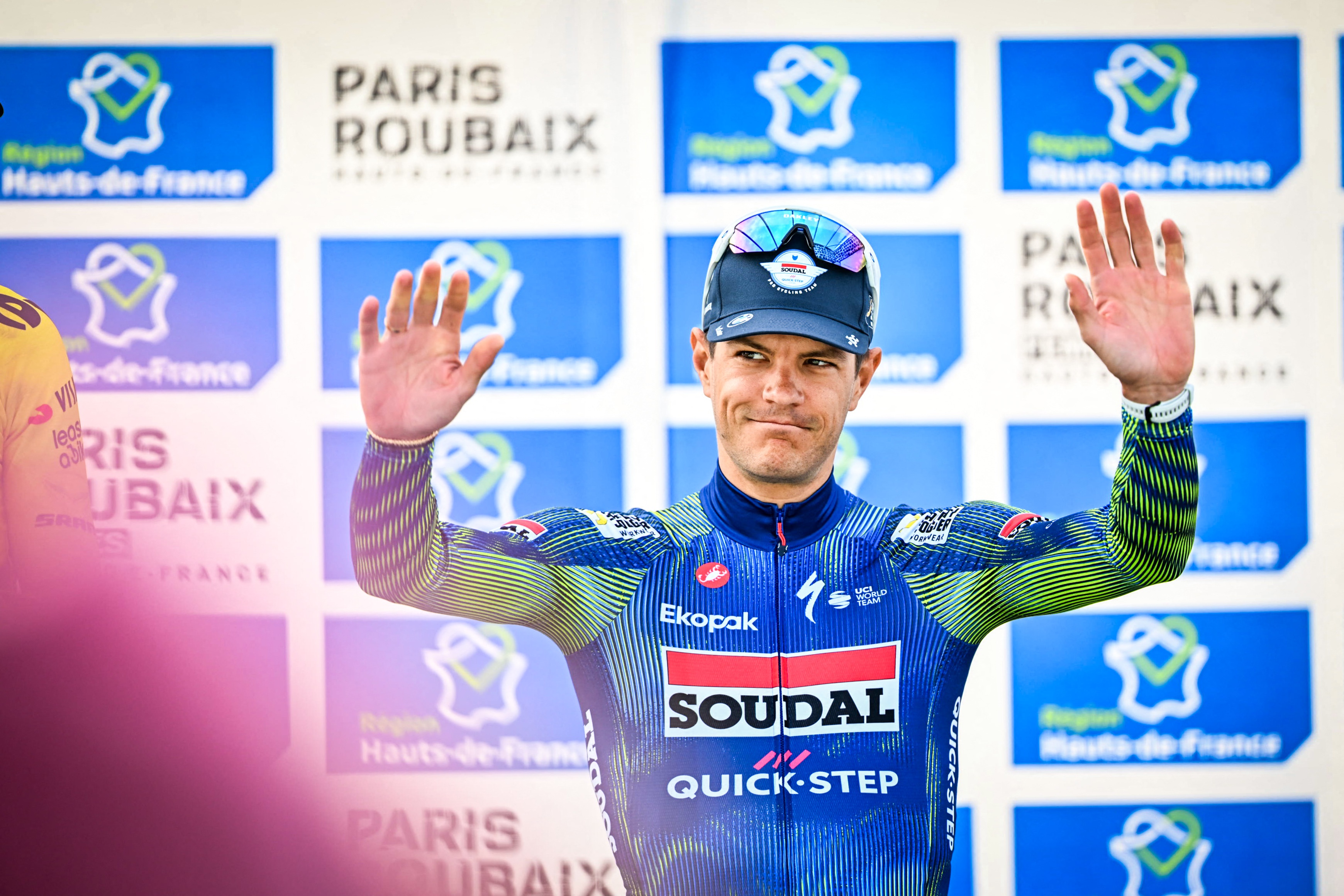 Jasper Stuyven celebrates and smiles with his hands in the air on the podium of Paris-Roubaix 2026