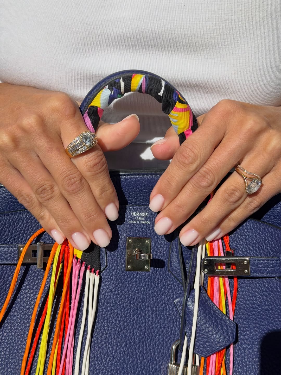 A woman with a milky manicure holding an Hermes handbag