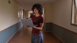 Dell XPS 13 being carried by a young person in a hallway, the laptop is open and they are looking at the screen