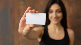 A woman holds up a blank card, wondering how to design a business card
