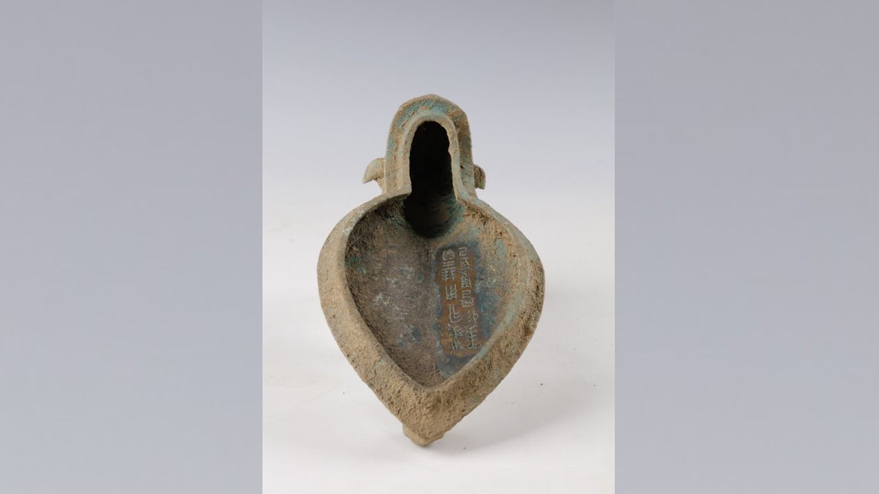 This bronze cover for a pottery vessel is inscribed with characters in Shang's "oracle bone" script.