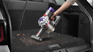 Dyson Car+Boat vacuum cleaner being used in the boot of a car