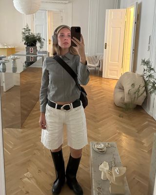 Karoline Beltner wearing longline white shorts and black leather riding boots