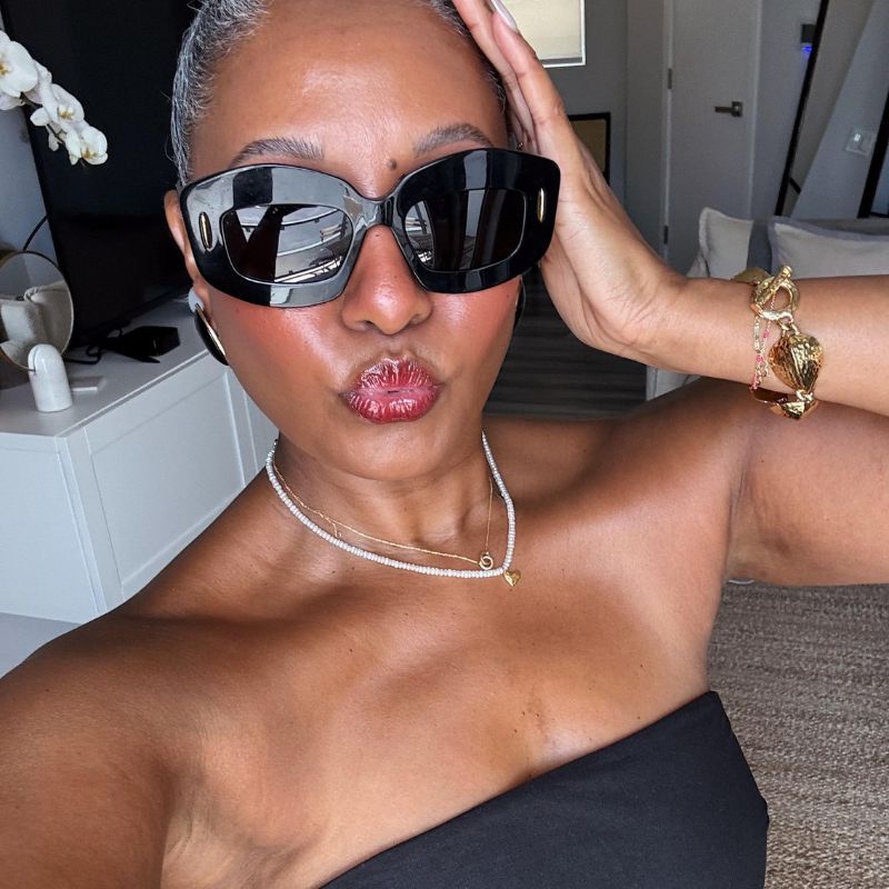 A selfie of Do you need a neck cream? wearing a strapless black top and black sunglasses with a bun hairstyle