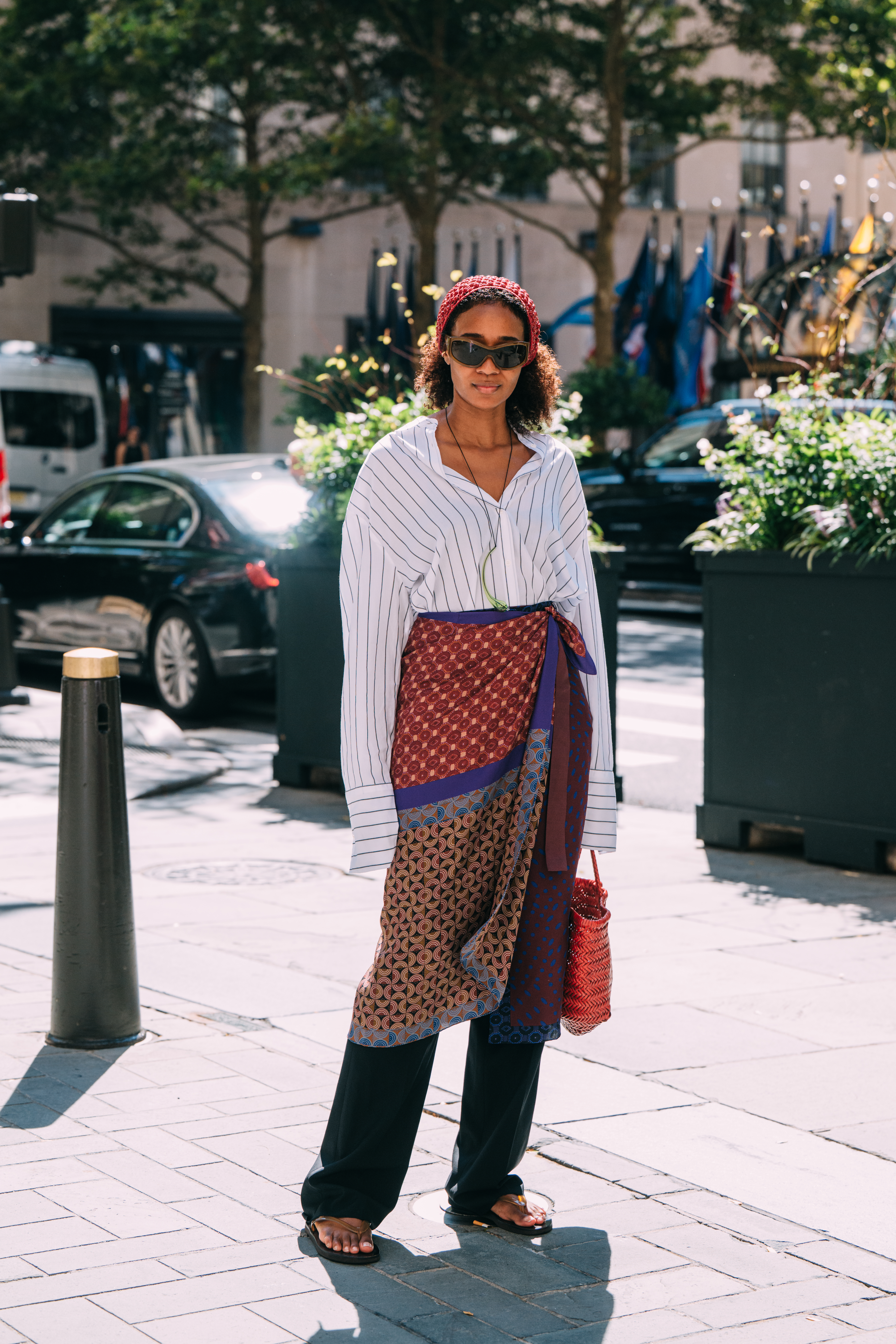 Woman wearing a striped shirt, scarf skirt, and black trousers.