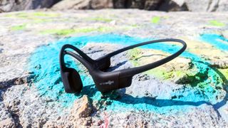 The Shokz OpenRun bone conduction headphones pictured on a stone surface