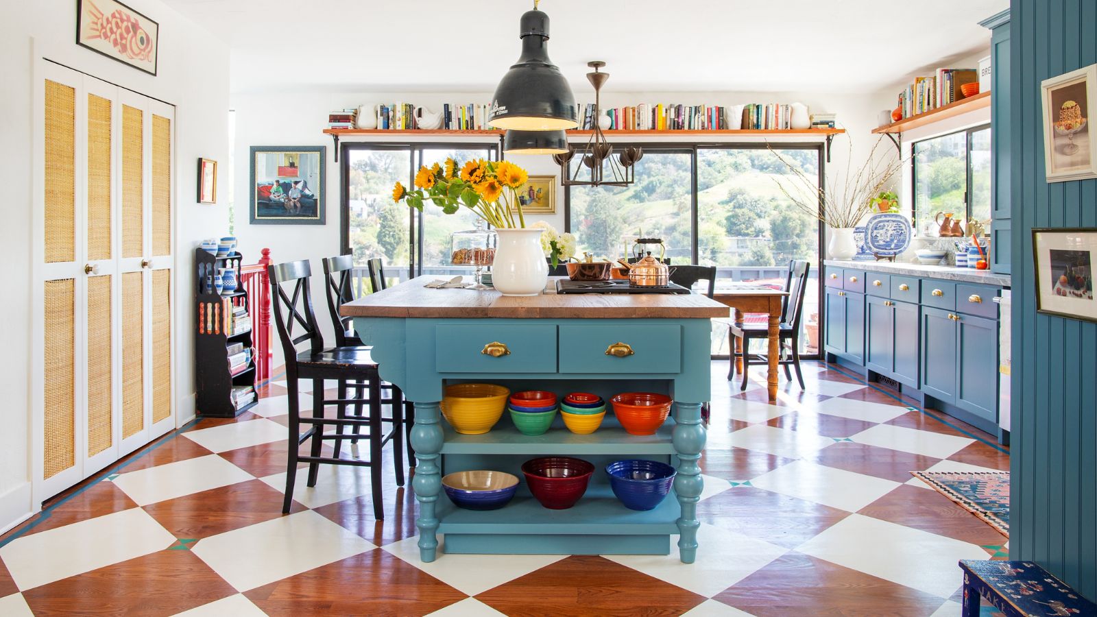 A large kitchen with blue cabinets and a painted wooden checkerboard floor design