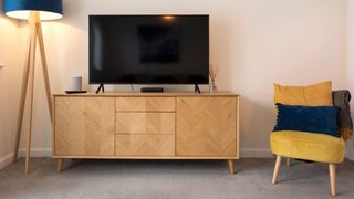 Lamp, chest with television on the top, and armchair with pillows