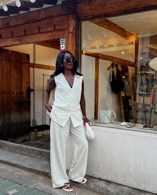 Aida Badji wearing white co-ord suit with white sandals and red pedicure