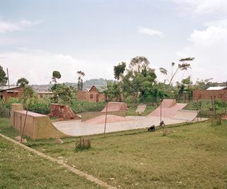 Skateboard ramps with an African village behind it.