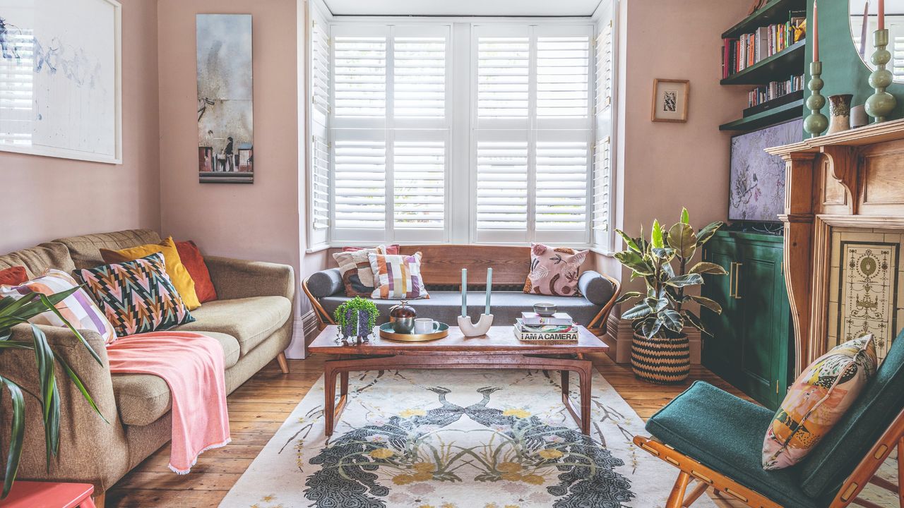 A light pink-painted living room withn a beige sofa and emerald green accent chair