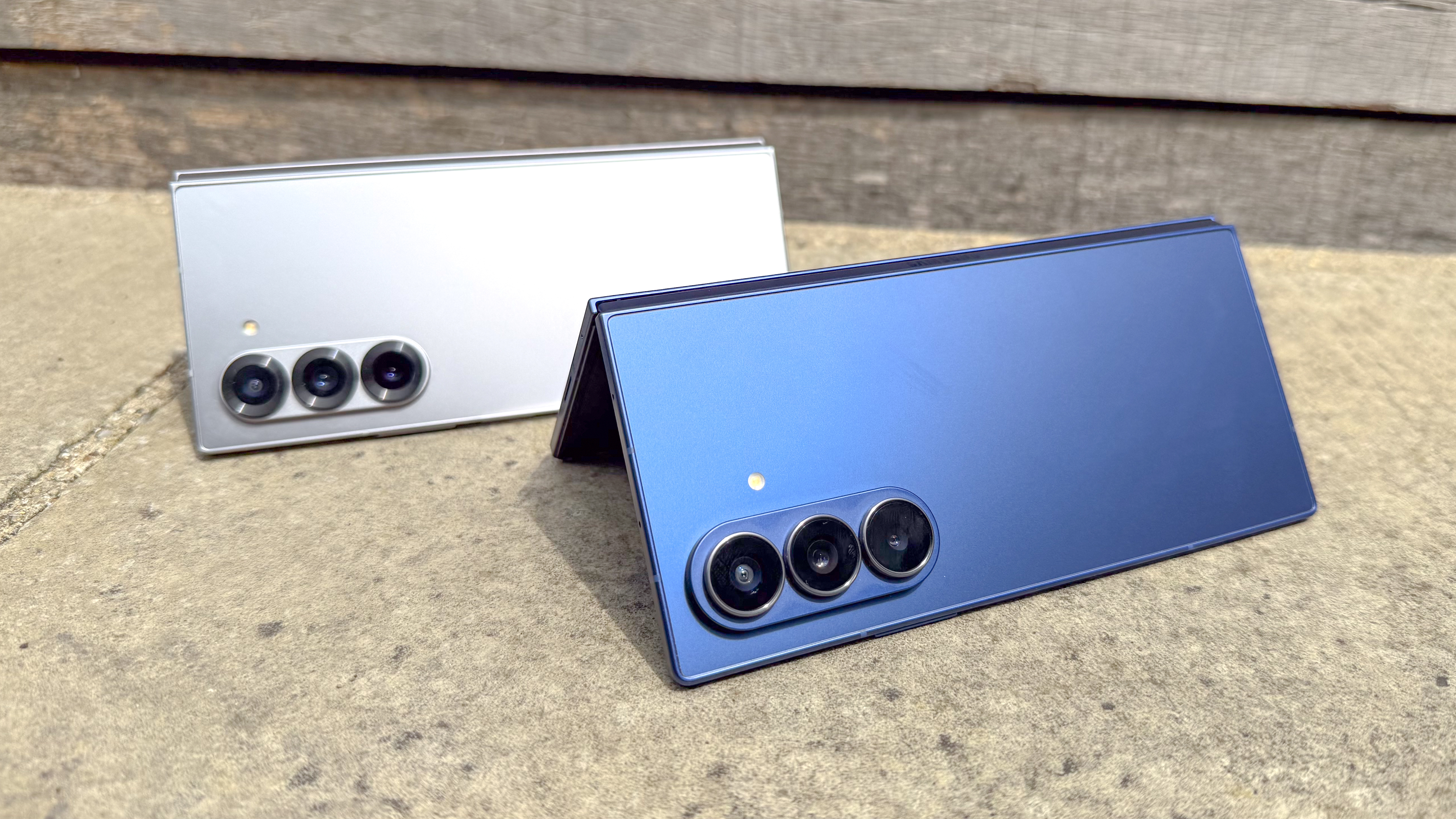 The Samsung Galaxy Z Fold 7 (blue, R) and Galaxy Z Fold 6 partly folded and placed in a "tent" shape