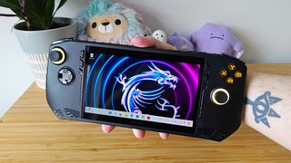 Hand holding MSI Claw handheld with logo wallpaper on screen