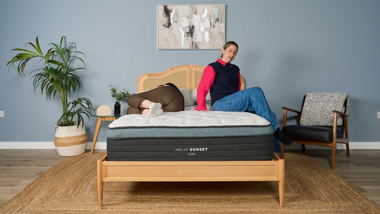 Tester Nicola Appleton moves around on the Helix Sunset Luxe Mattress while another tester, Ruth Jones, lies still next to her.
