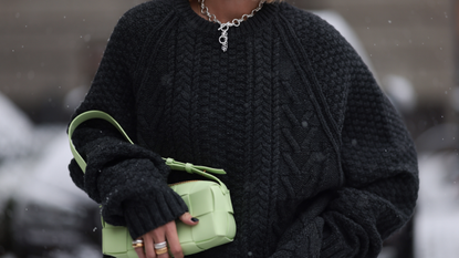 Nadine Berneis seen wearing Black Palms the label black wool cable knit sweater, silver earrings, Glambou silver chain necklace, Bottega Veneta light green / pastel green leather bag, on November 29, 2023 in Berlin, Germany. 