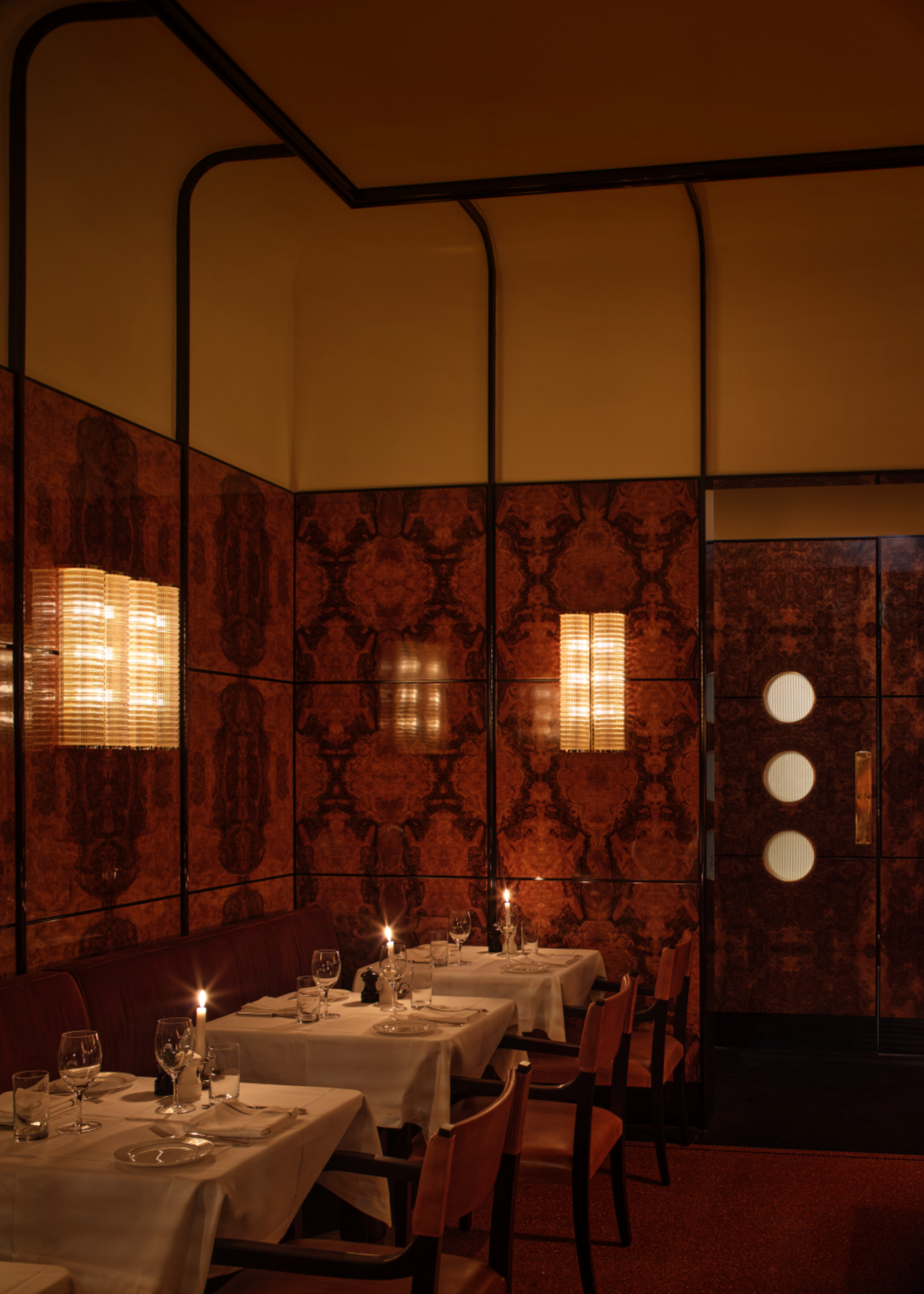 Dimly lit dining area with burl wood walls and murano glass scones
