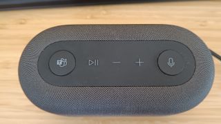 A grey Microsoft Audio Dock sitting on a wooden desk