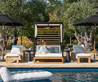 outdoor covered lounger and matching furniture next to a pool