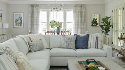 living room with white corner sofas and assorted white and blue cushions with light-coloured footstool
