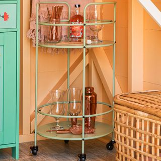 orange painted beach hut with green cocktail trolley