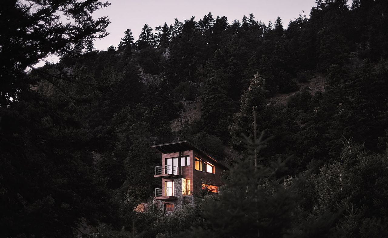 Timber chalet perched on a slope in the midst of trees 