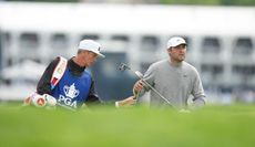 Scottie Scheffler hands his club to his caddie