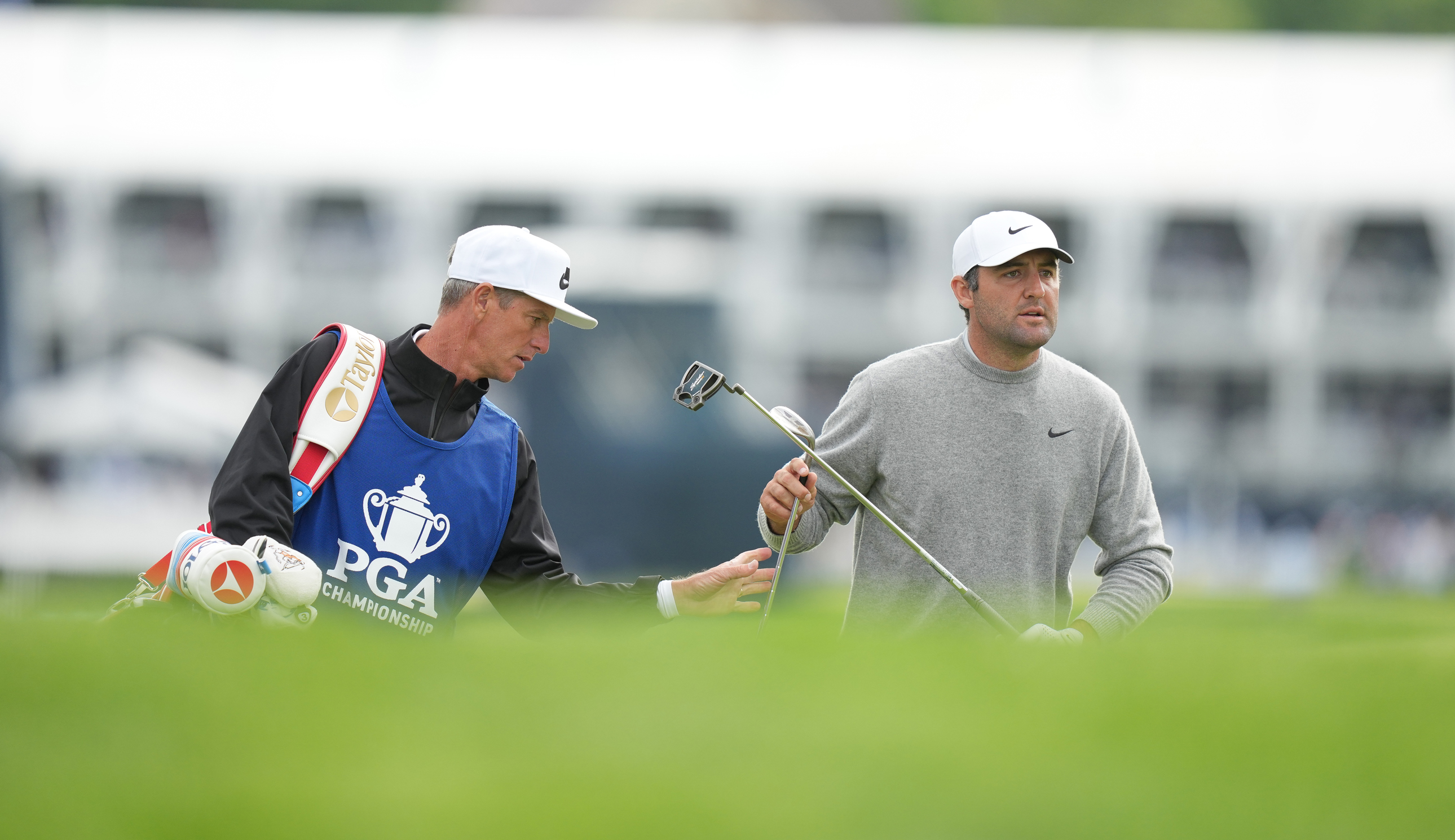 Scottie Scheffler hands his club to his caddie