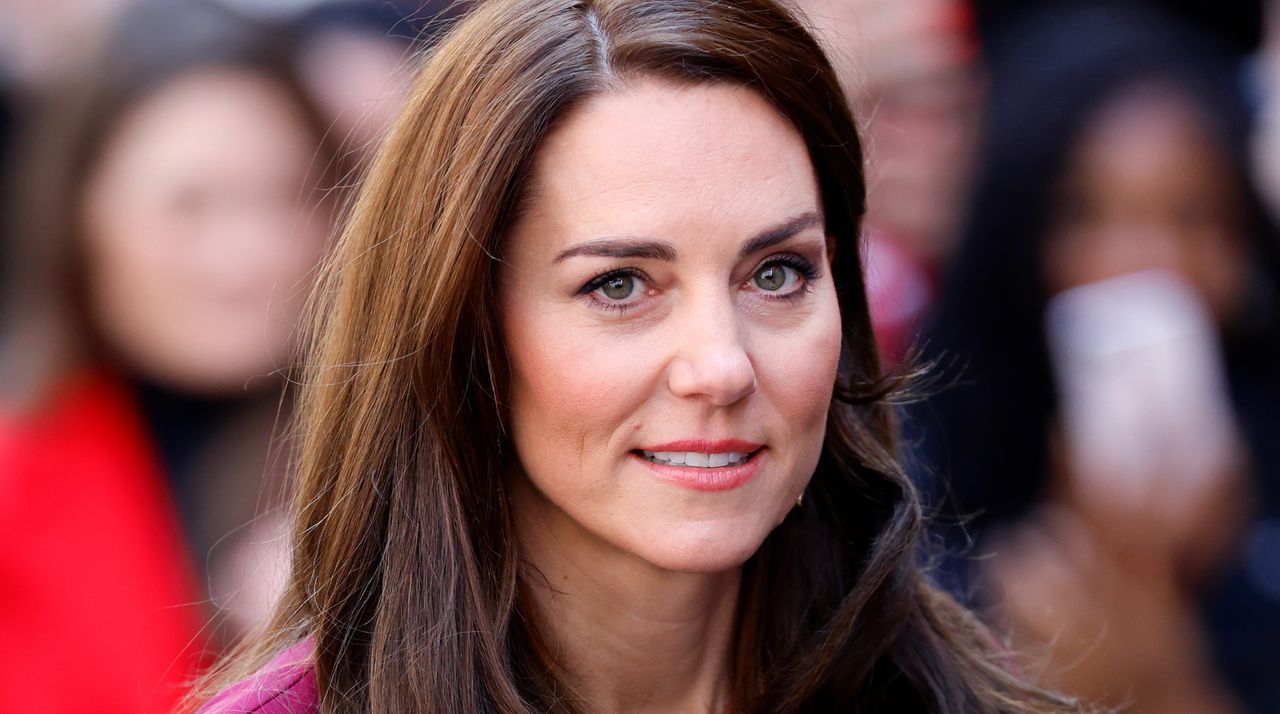 Kate Middleton has long brown hair and is wearing a pink dress