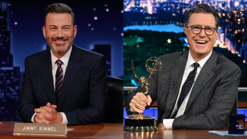 From left to right: Jimmy Kimmel smiling at his desk and Stephen Colbert smiling and holding his Emmy in his left hand while sitting at his desk.