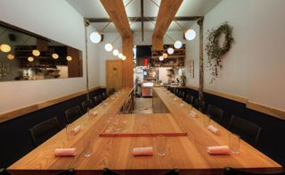 Inside Brooklyn’s Semilla featuring a large wooden table which stretches through the restaurant.